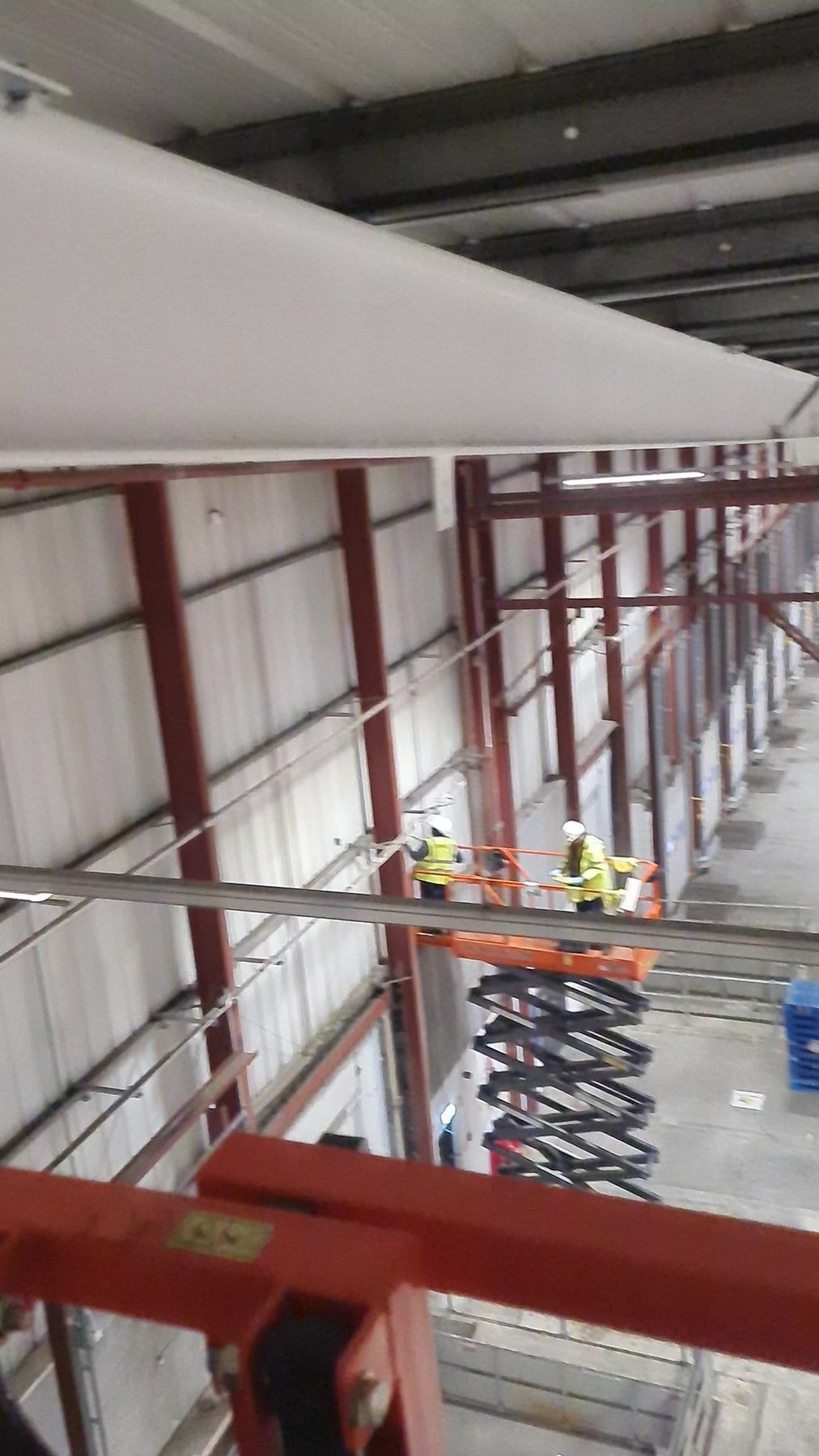 Two operatives cleaning high level steelwork from a scissor lift