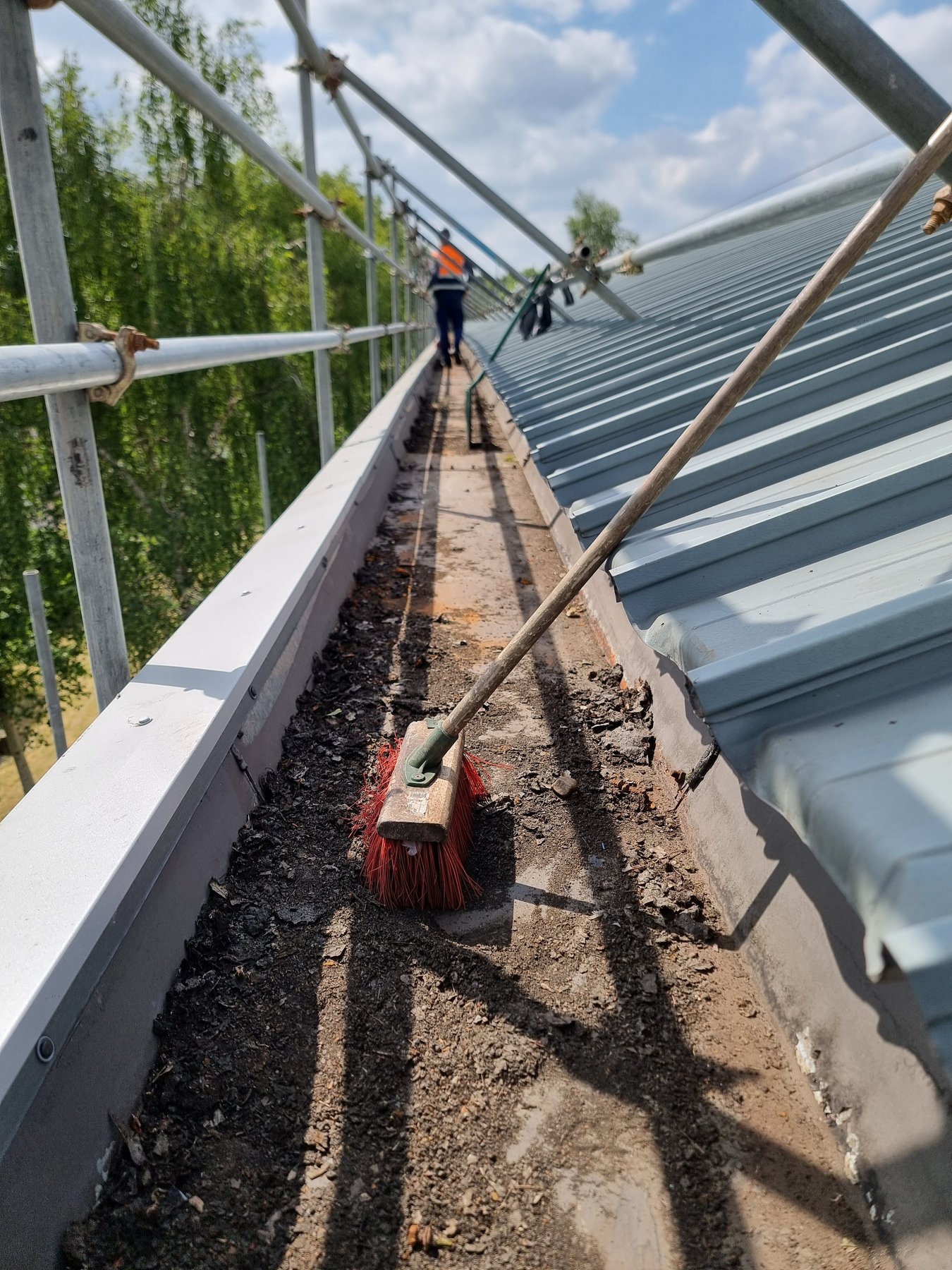 Debris and silt being brushed out of an industrial valley gutter